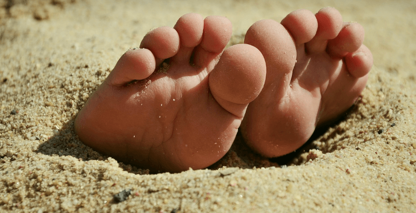 모래 사장에 발이 덮혀 있는 모습