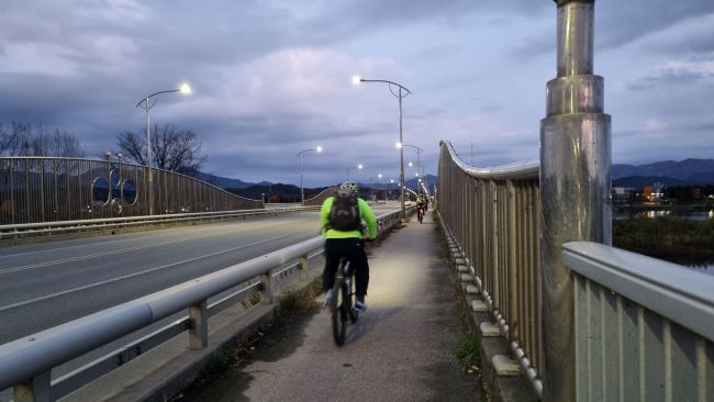 가로등 불빛이 들어 온 신매대교 위&#44; 그린색 자켓 입고 달리는 자전거 1&#44;