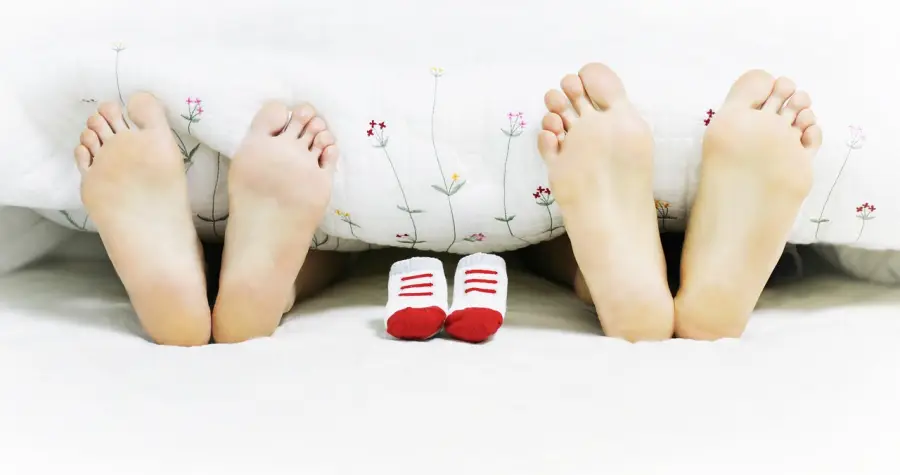 신생아 특례대출 - 흰 이불 안 맨발 뚜쌍 가운데 빨간 아기양말