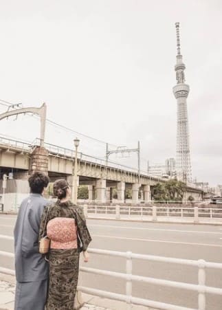 커플이 일본의 전통의상을 입고 멀리있는 타워를 바라보고 있다.