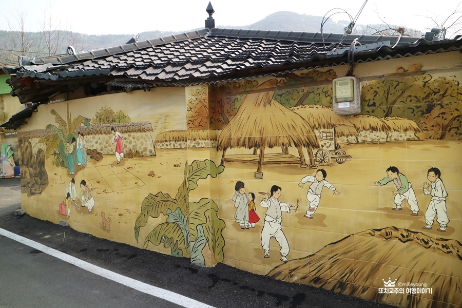 까만 지붕 건물 담벼락에 조선시대 아이들이 놀고 있는 벽화가 그려져있다