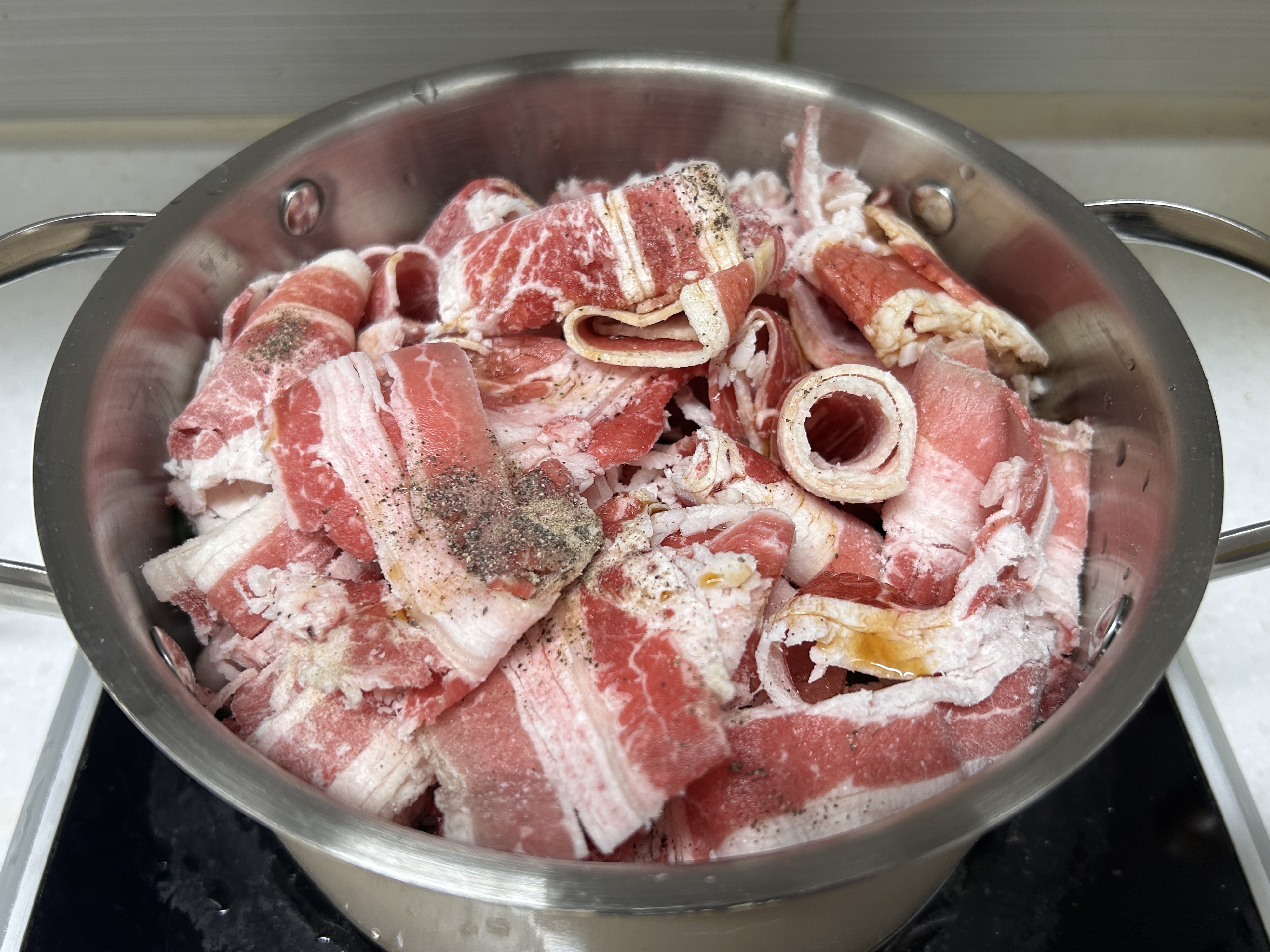 가열 전 우삼겹숙주찜&amp;#44; 냄비 뚜껑이 열려 있다.