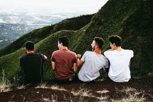 산 정상에 앉아서 풍경을 바라보며 웃고 있는 친구들