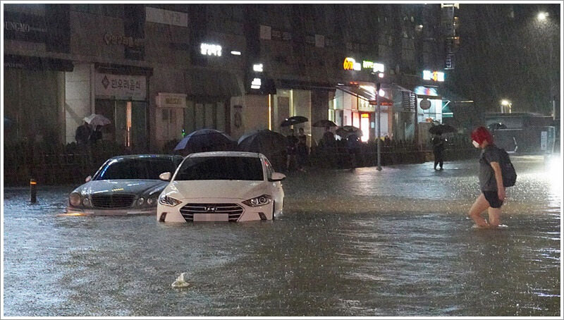 폭우로 인해 침수 된 차량과 그 주변을 서성이는 사람들
