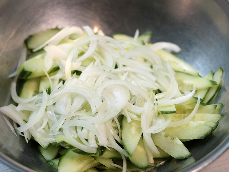 채썬 양파, 오이, 반으로 자른 방울 토마토 볼에 담기