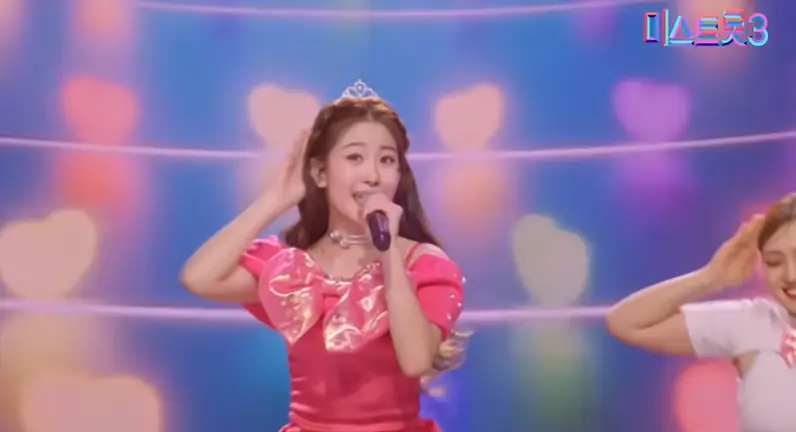 미스트롯3- 무지개 무대 앞 분홍색 큰 리본이 달린 분홍색 드레스 입고 왼손으로 마이크를 들고 귀엽게 노래하는 오유진