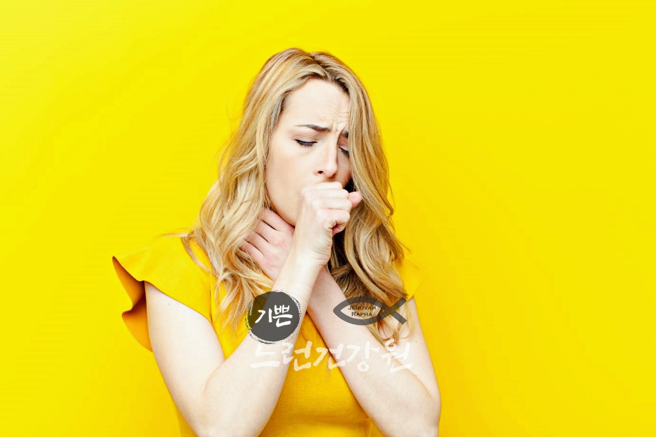 노란색 옷을 입고 목을 잡으며 기침을 하는 여성