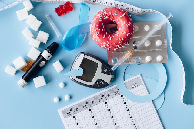 당뇨병과 관련된 설탕&#44; 도넛&#44; 혈당측정기&#44; 주사기&#44; 인슐린&#44; 혈당 기록지가 널부러져 있는 사진