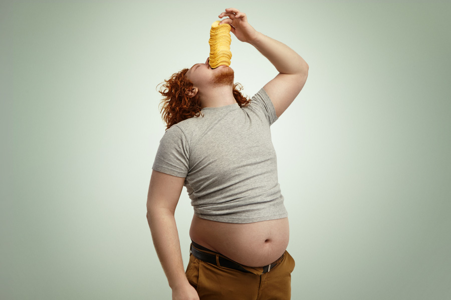 obese-overweight-redhead-man-throwing-head-back-stuffing-big-pile-potato-chips-into-mouth-enjoying-unhealthy-junk-food-wearing-undersized-t-shirt-with-belly-sticking-out-900
