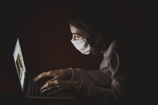 마스크를 쓴 여성 분이 어두운 곳에서 컴퓨터 하는 모습
