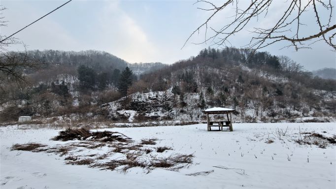 자전거 길 옆 눈쌓인 들판 한가운데 원두막 쉼터&#44; 뒤로는 야산&#44;