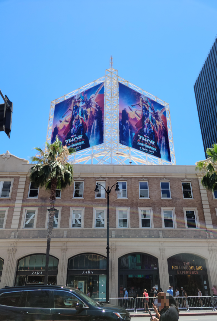 토르 영화의 광고판이 건물 위에 세워져 있다. 똑같은 포스터 두 개가 사선 방향으로 나란하게 세워져 있다. 