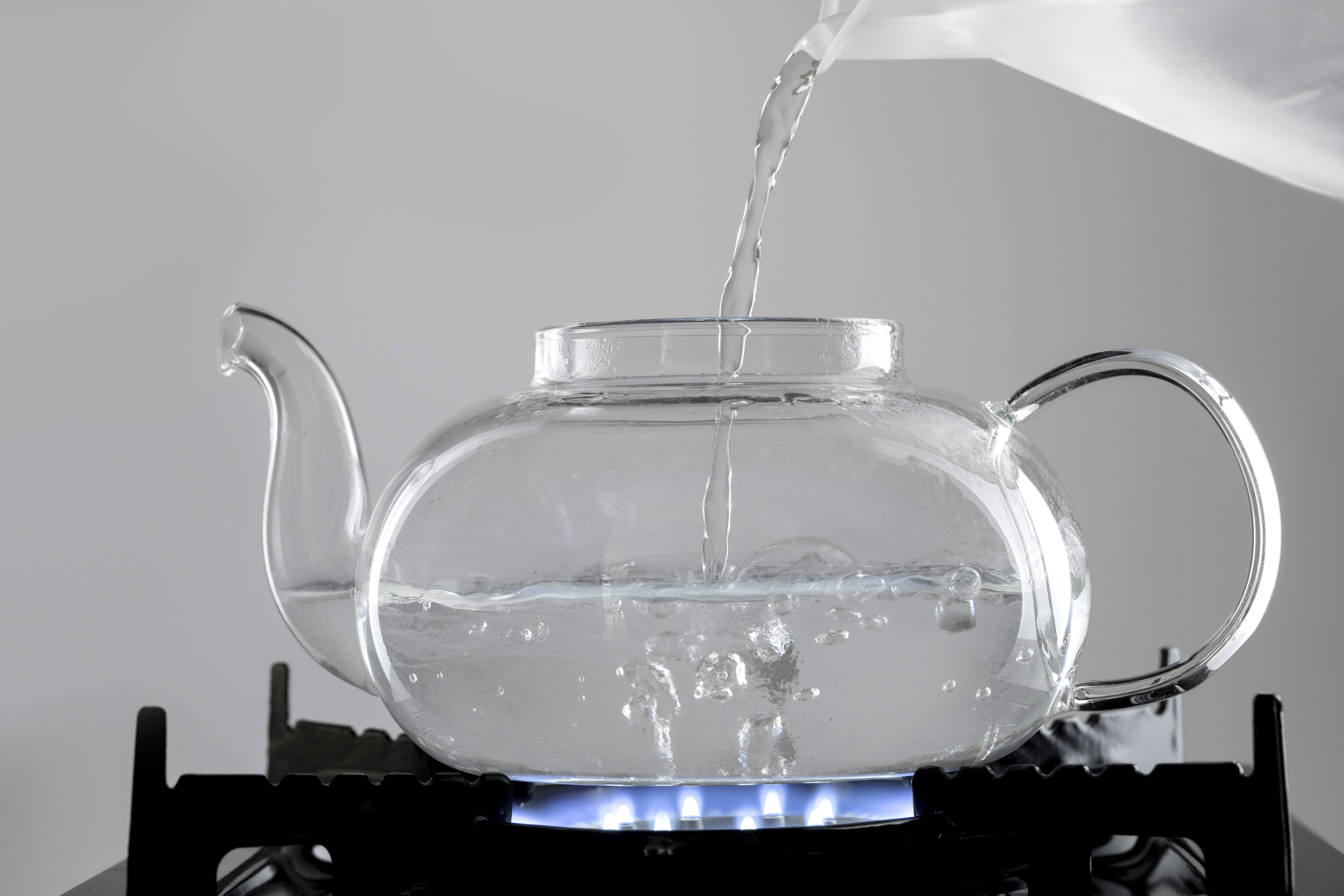 가스레인지에 불을 켜고&#44; 그 위에 유리주전자를 놓고 물을 반쯤 부으면서&#44; 끓이고 있는 사진