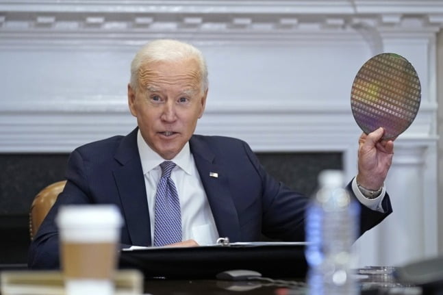 조 바이든 미국 대통령이 2021년 백악관에서 열린 반도체 CEO들과의 화상 회의에서 반도체 웨이퍼를 집어들었다