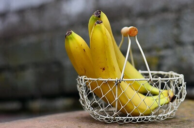 철재로 만들어진 바구니에 담겨있는 바나나 세 개
