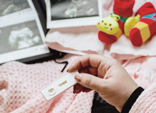 임신 테스트기에 두줄이 있고 저 멀리 아기 초음파 사진이 보이는 사진