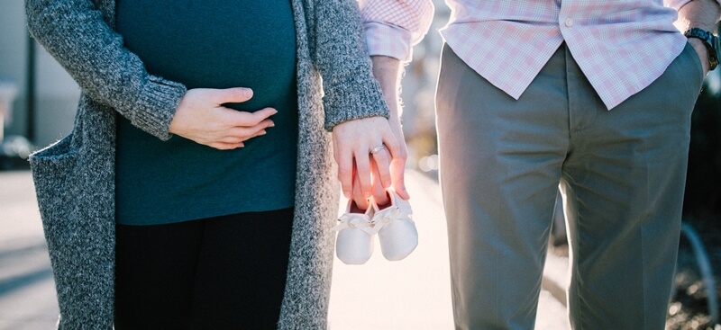 임신한-여자와-남자가-아기-신발을-함께-들고있는-사진