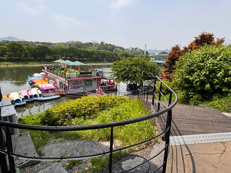 춘천 호수 산책길과 오리보트 선착장 풍경.
K-Lakeside duck boat dock with pedal boats near the trail in Chuncheon.