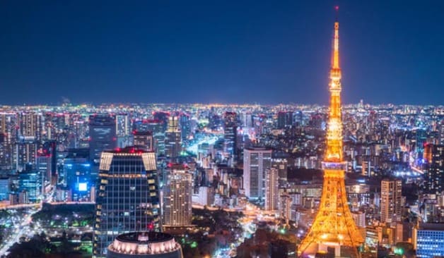 도쿄 타워가 노란색 불빛으로 빛나고 있고 다른 빌딩들도 형형색색으로 빛나고 있는 도심의 야경