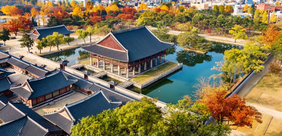 가을 단풍에 둘러싸인 경복궁 경회루의 전경, 고즈넉한 기와지붕과 맑은 연못이 어우러진 풍경