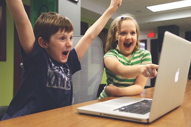 아이들이 컴퓨터 앞에서 좋아하고 있다.
