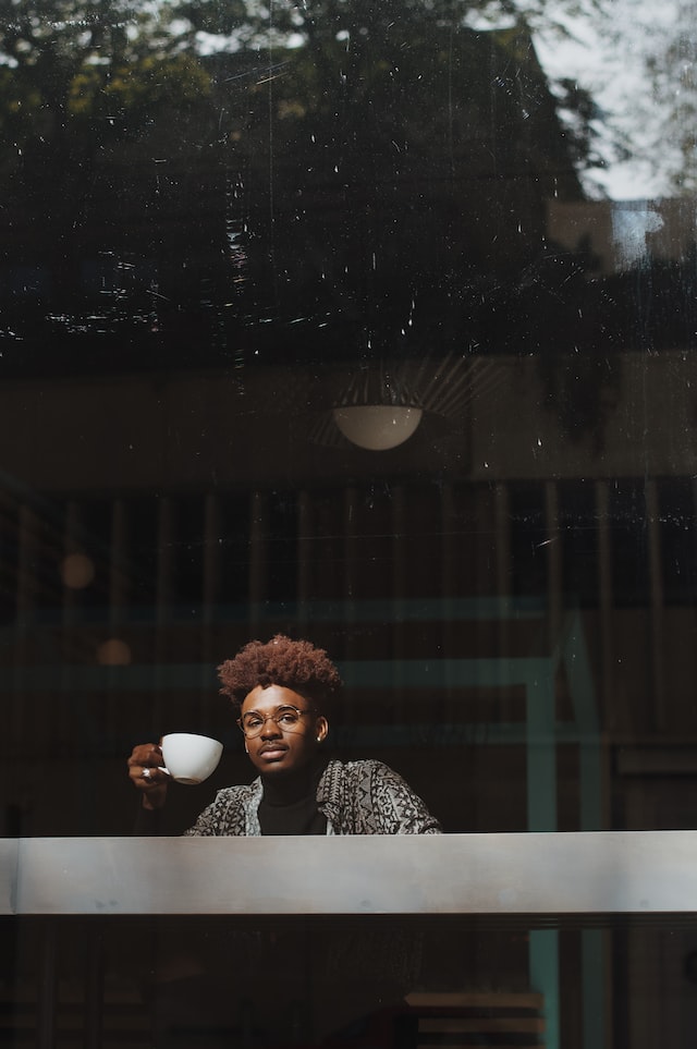 한-사람이-카페-안에서-커피를-마시며-창밖을-바라보는-사진