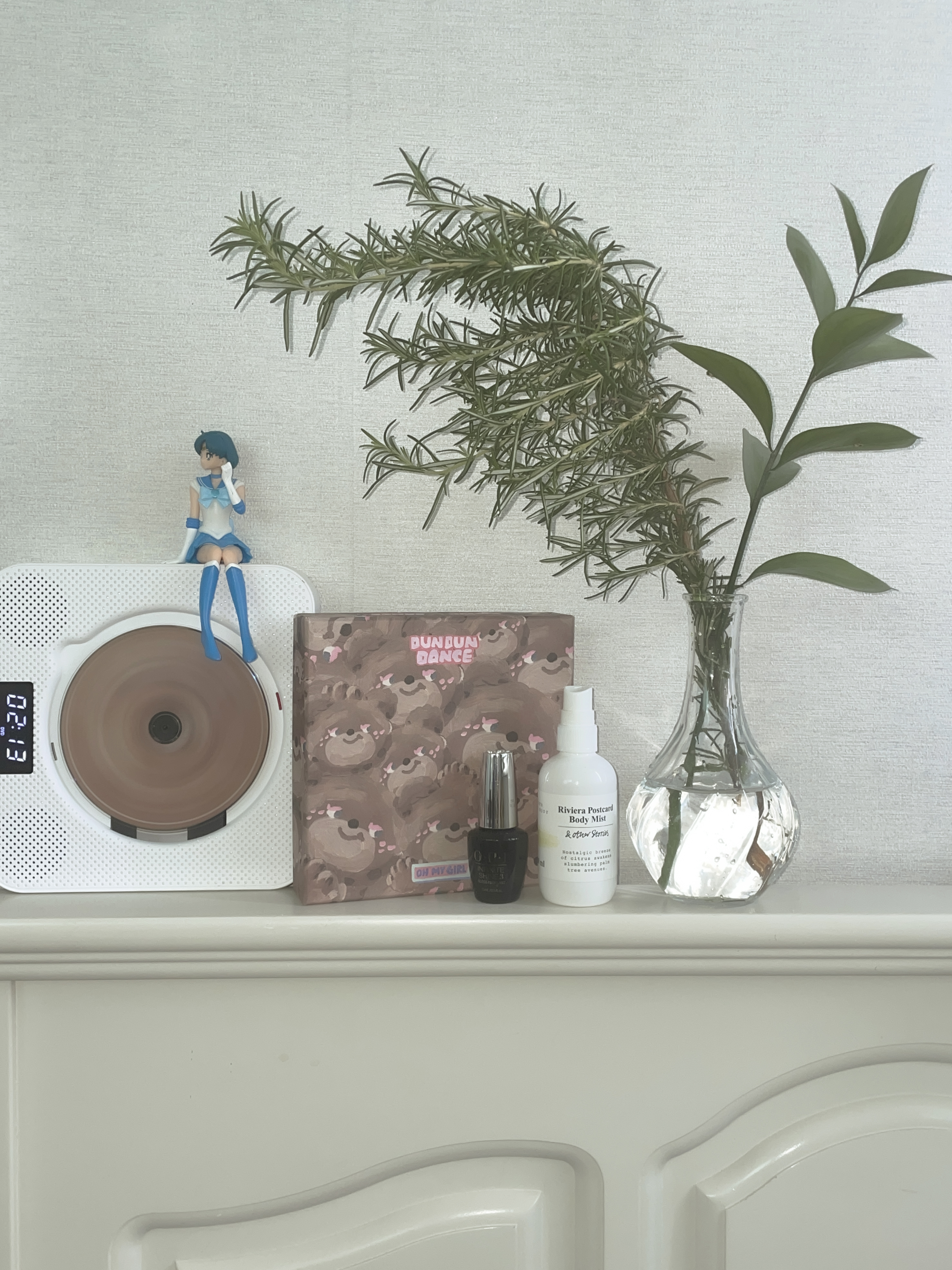 CD player next to the rosemary in a vase
