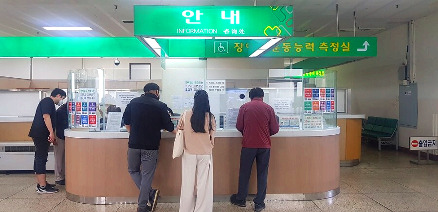 초록색-간판의-인포메이션-앞에-사람들이-서있는-모습을-찍은-사진
