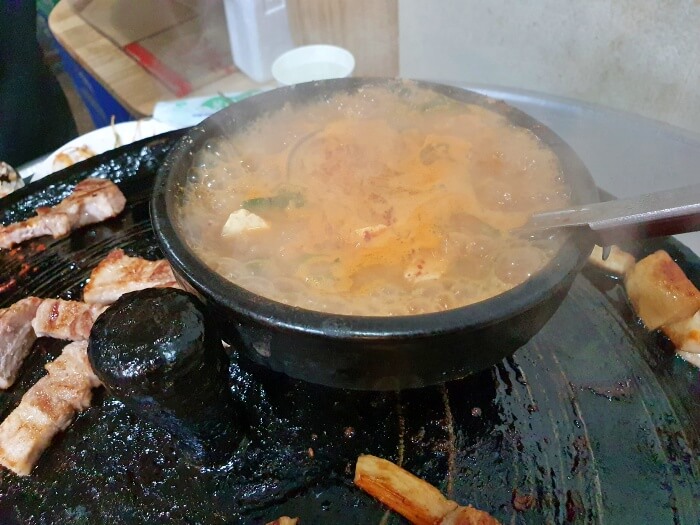 솥뚜껑 위에 올라간 청국장 뚝배기 사진입니다.