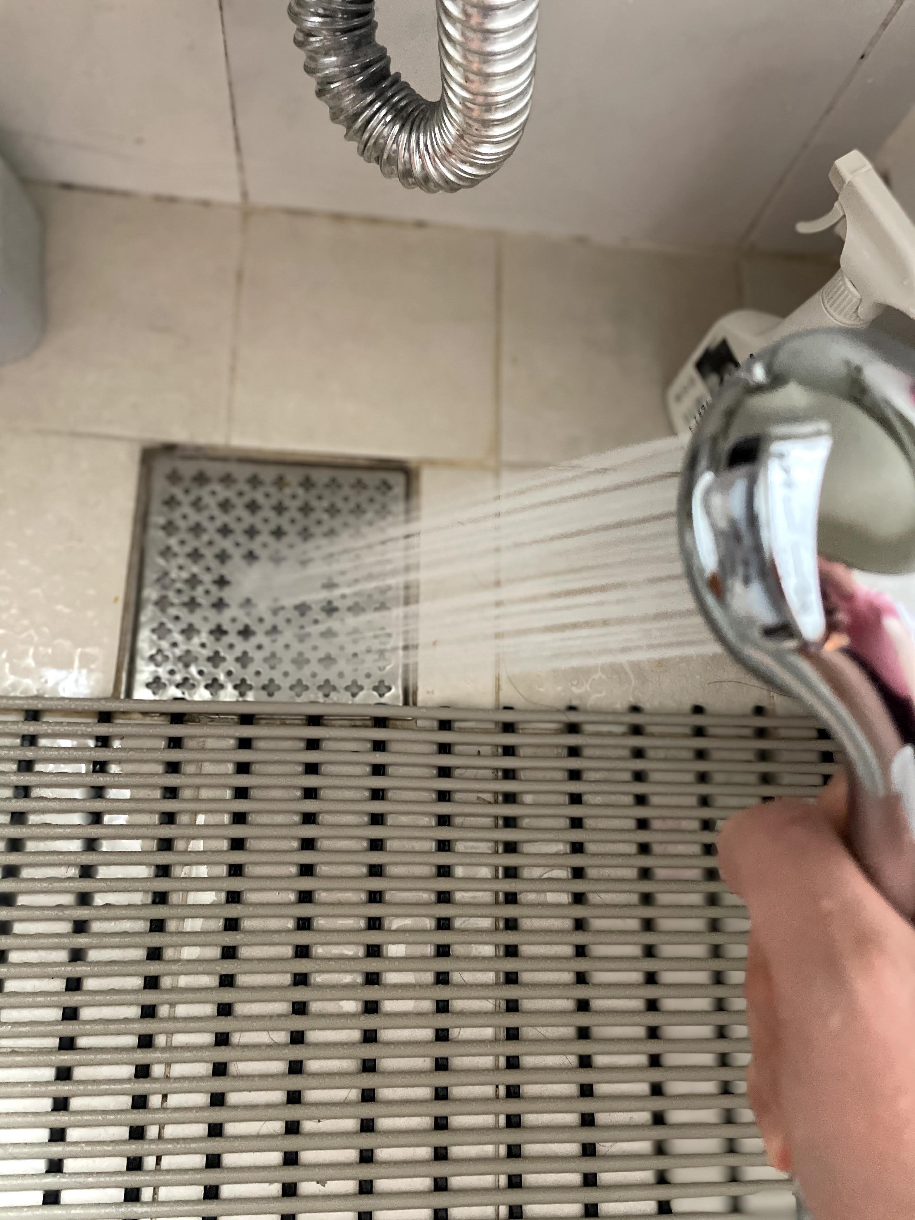 샤워기로 뜨거운 물을 뿌려 욕실 배수구를 소독하는 사진