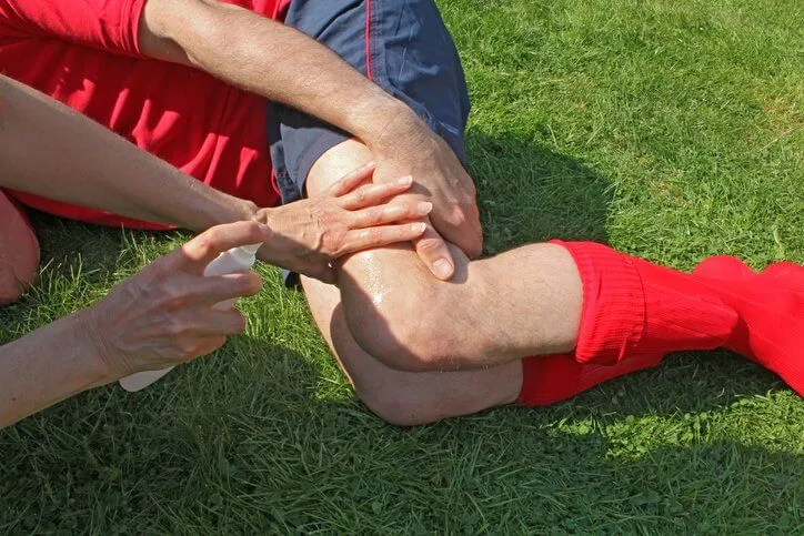 햄스트링 부상을 당한 사람이 쓰저려서 허벅지를 붙잡고 있다.