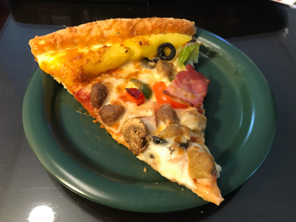 피자헛의 수퍼슈프림 피자 라지 사이즈에 리치 골드 엣지를 추가한 한 조각을 접시에 담은 모습.