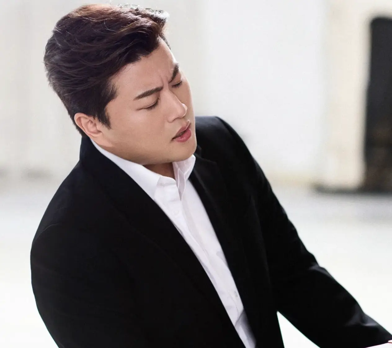 검은 쟈켓 흰 셔츠를 입고 피아노를 치며 노래하는 김호중