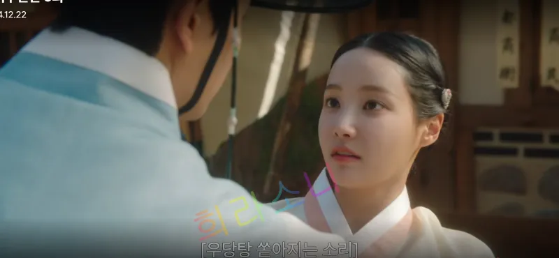 밝은 날씨&amp;#44; 미령이 흰색과 연분홍색 한복을 입고 놀란 표정으로 앞에 있는 성도겸을 바라보고 있다. 상도겸은 연한 파란색 한복을 입고 갓을 쓰고 있다. 자막은 