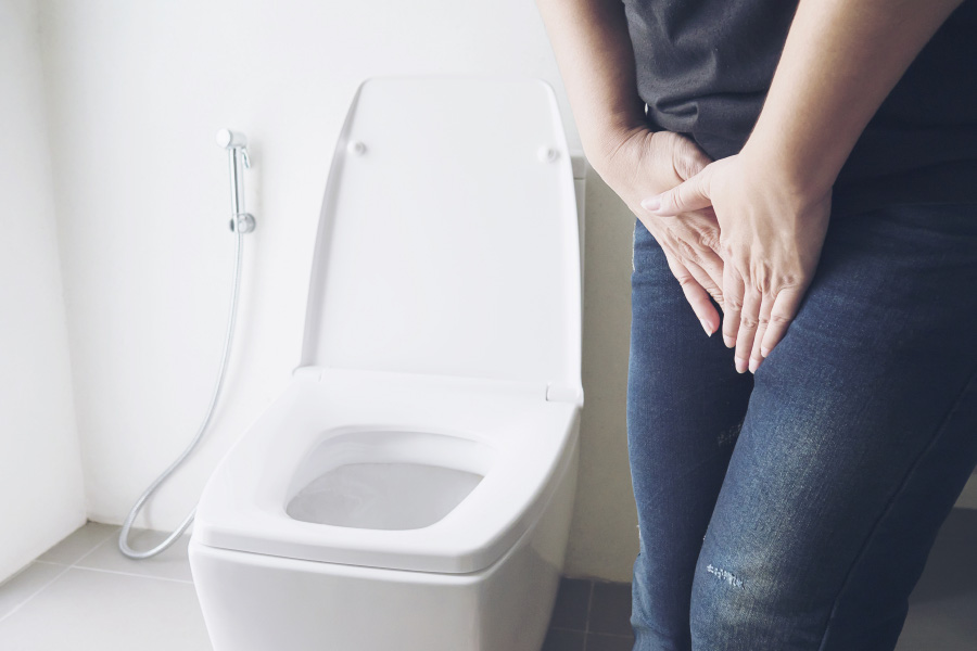 한 여성이 방광염으로 인한 소변을 자주 보는 소변빈삭증 때문에 소변을 참으면 화장실에 서 있는 사진