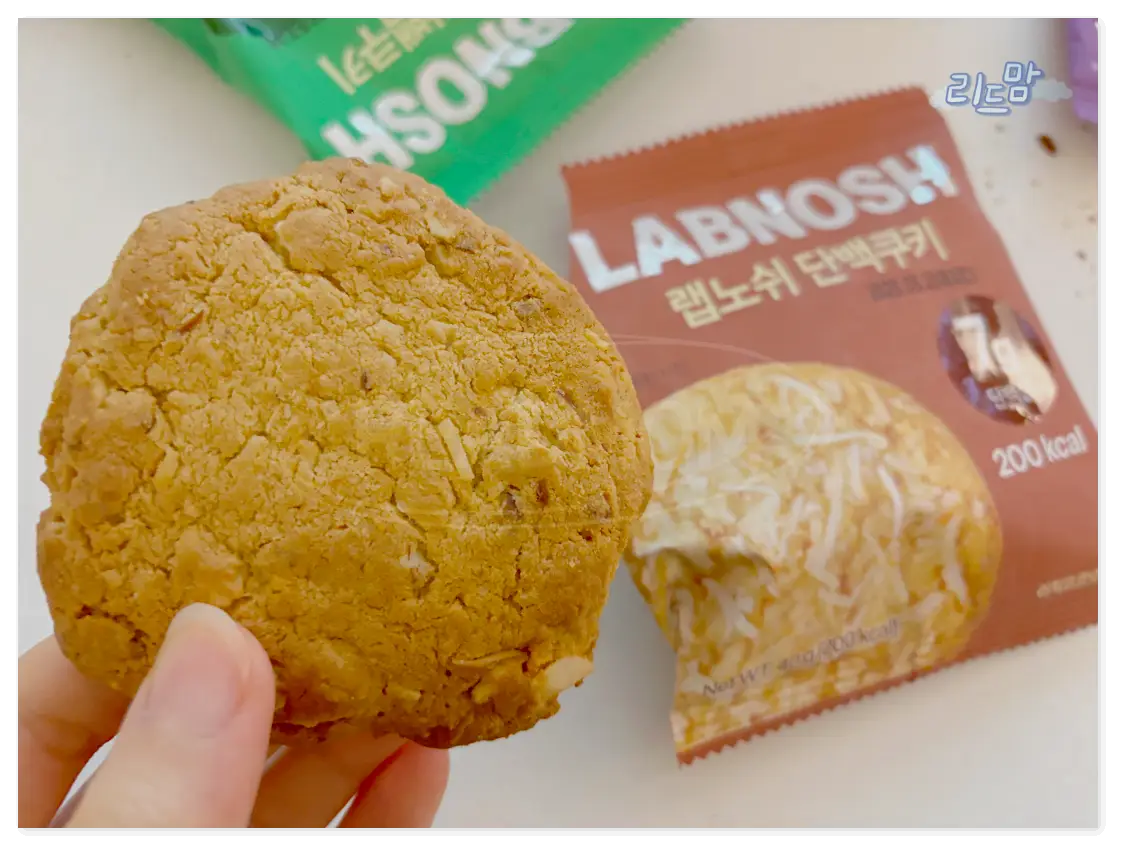 랩노쉬-단백질쿠키-버터코코넛-손-갈색포장지-초록색포장지