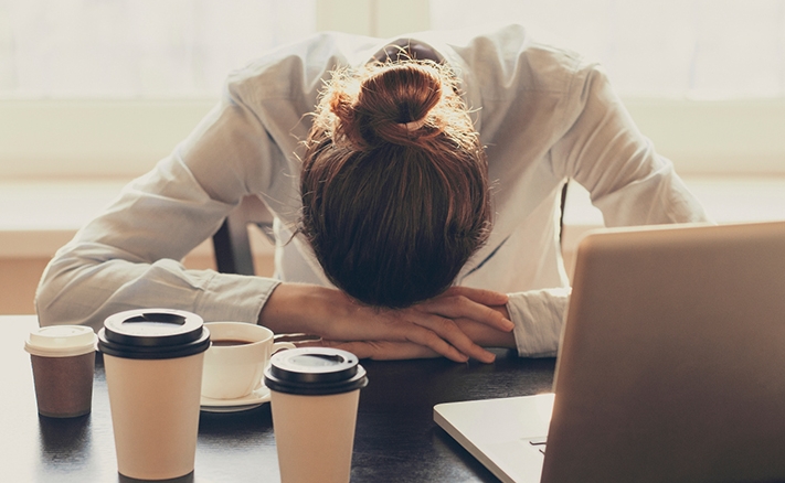 수면부족으로 인한 피곤으로 책상에 엎드려 있는 여성