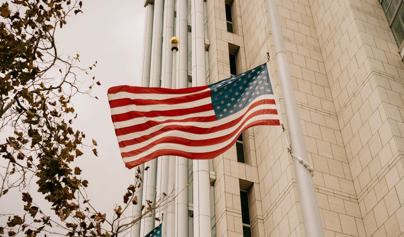 U.S. flag waving in front of a government building – symbolizing American visa approval, ESTA entry, and immigration control