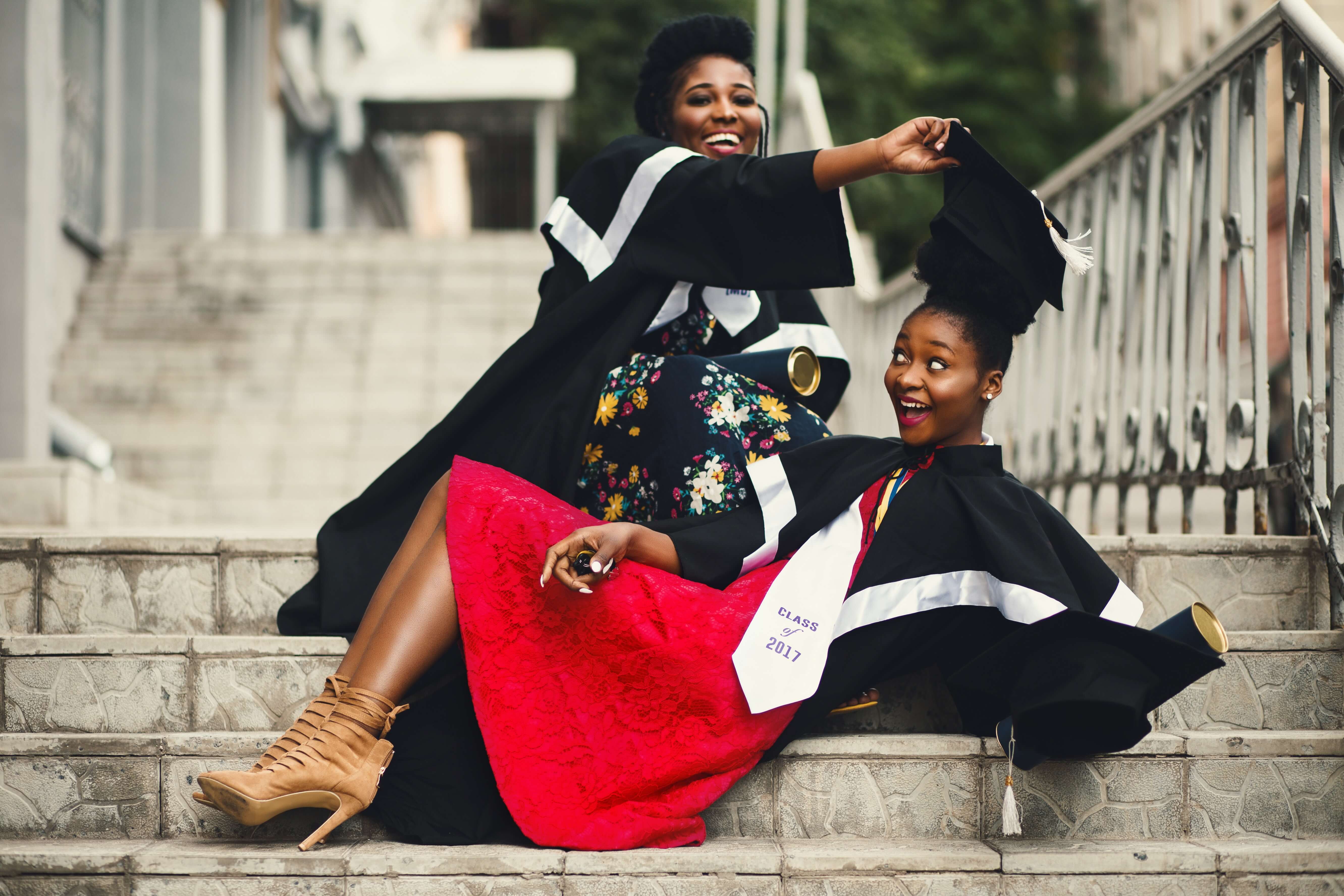 두 여성이 졸업가운과 학사모를 쓰고 장난치는 장면