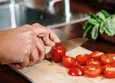 도마 위에서 방울 토마토를 자르고 있는 남자의 손