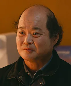 어느 실내를 배경으로 대머리에 검은 점퍼를 입고 있는 유괴의 날 박철원 캐릭터