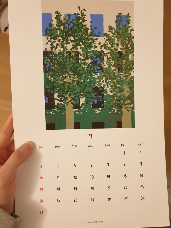 플라타너스 나뭇잎이 점묘화처럼 표현되어 있고 뒤에는 희미하게 건물이 보이는 일러스트가 그려진 웜그레이테일 7월 달력.