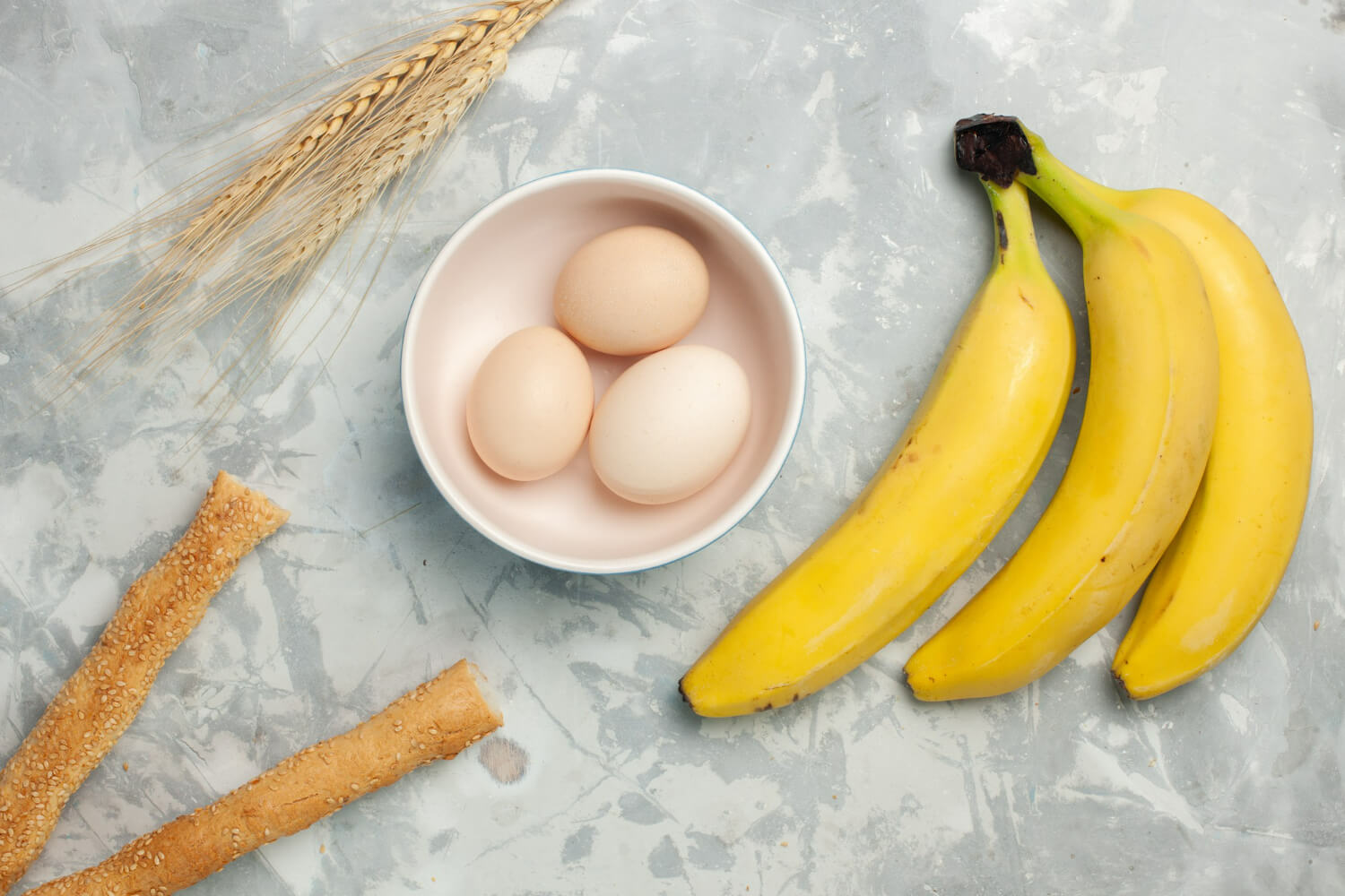 달걀 3개가 접시에 담겨있고 그 옆에 바나나가 놓여져 있다.