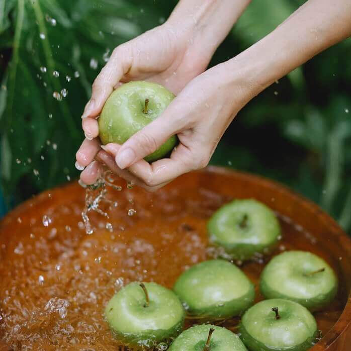 물 담긴 대야에 여러 알의 연두색 사과가 들어있고&#44; 그 중 한 개를 닦고 있는 여자의 손