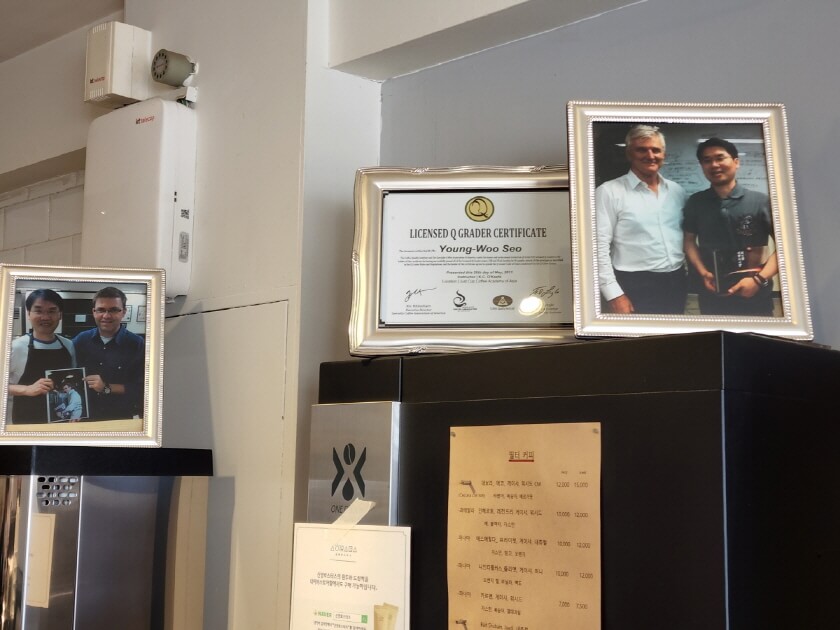 Q-Grader Certificate이라고 되어 있는 커피 관련 자격증. 사장님이 외국인과 찍은 사진이 전시되어 있다.
