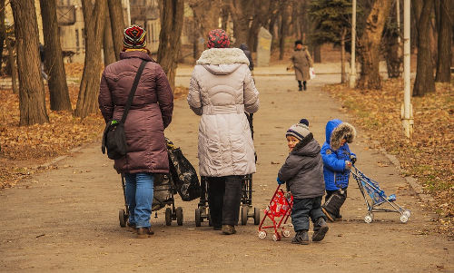알트태그-유모차를 끄는 엄마와 아이들이 공원을 산책하고 있다.