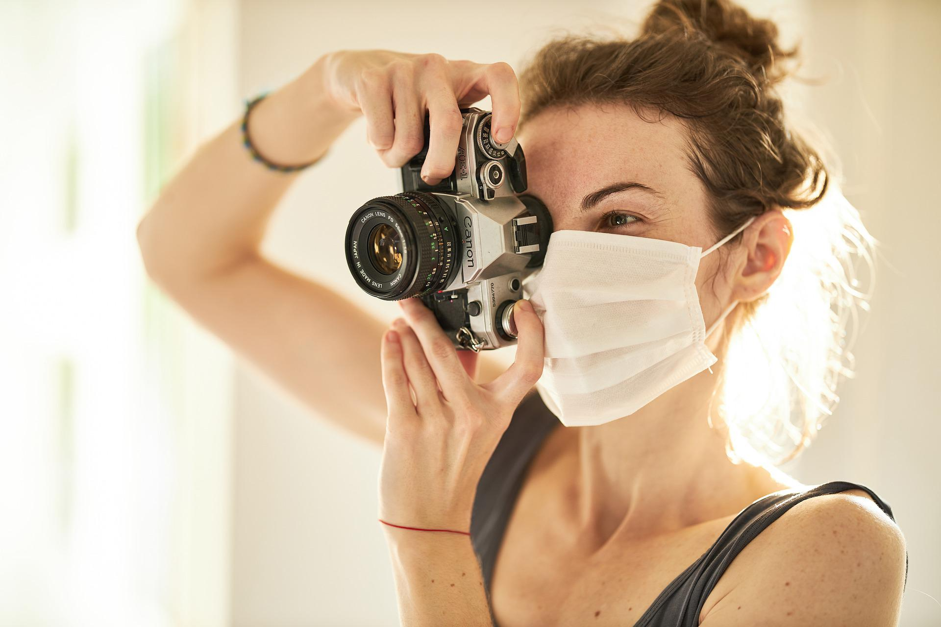 검은회색 나시를 입고 마스크를 쓴 상태로 카메라를 이용해 사진을 찍고있는 여성 