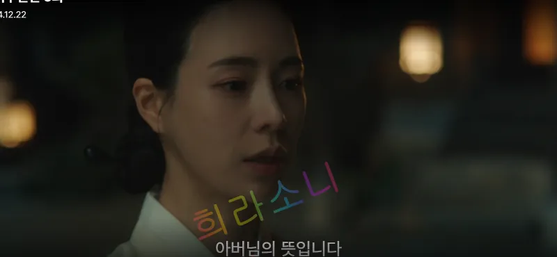 어두운 배경에서 흰색 한복을 입은 태영이 고요하고 담담한 표정으로 말을 하고 있다. 배경은 실내이며 불빛이 은은하게 비치고 있다. 자막은 