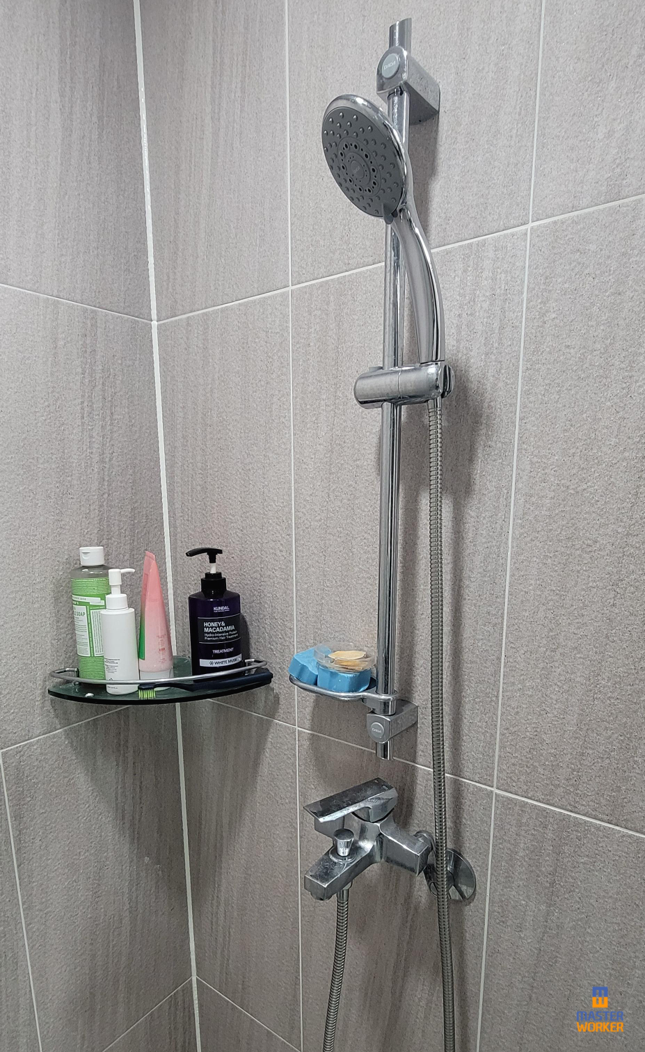 안방 화장실의 샤워 수전의 호스가 행거에 걸려있는 모습