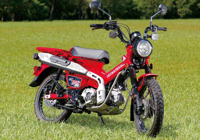 혼다 ct125 오토바이 측면 사진 마치 곤충처럼 생겼다. 잔디밭 위에 오토바이가 세워져 있다